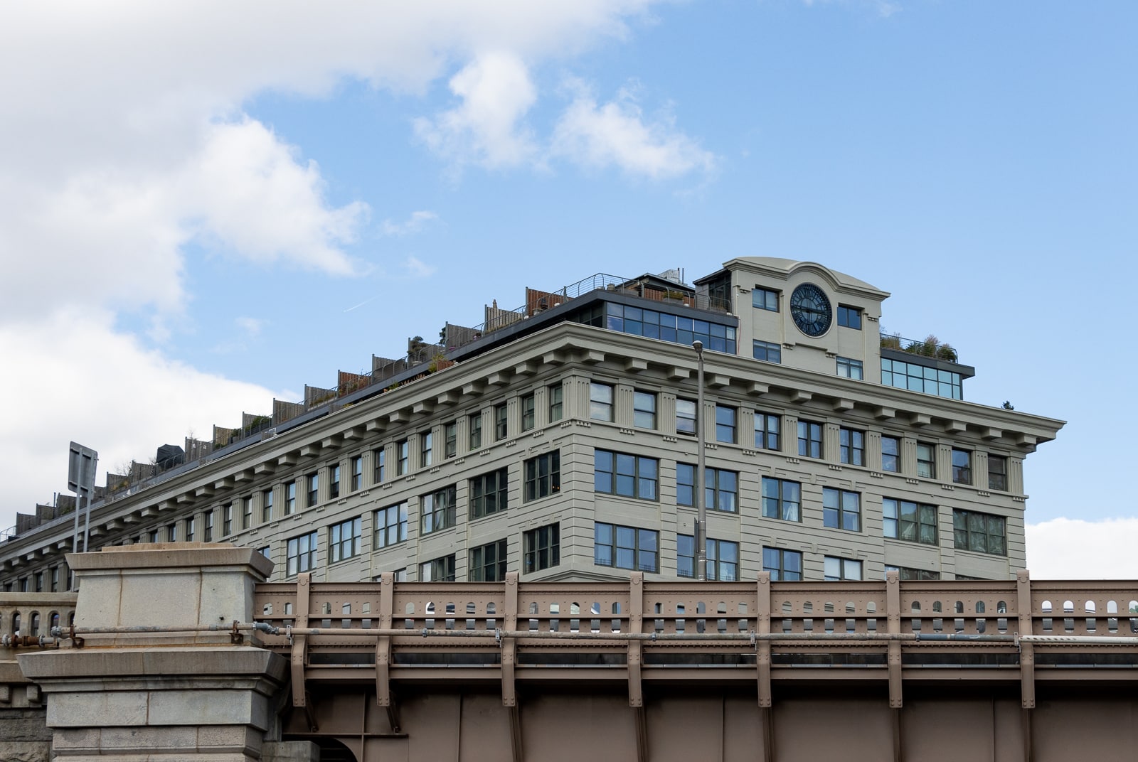 the upper stories of the concrete building as seen from behind the bqe expressway