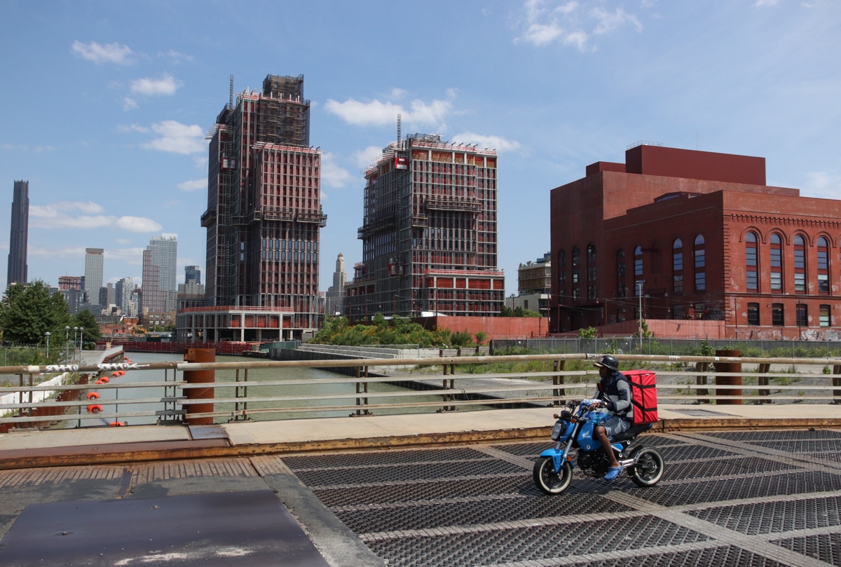 cyclist rides past two towers under construction