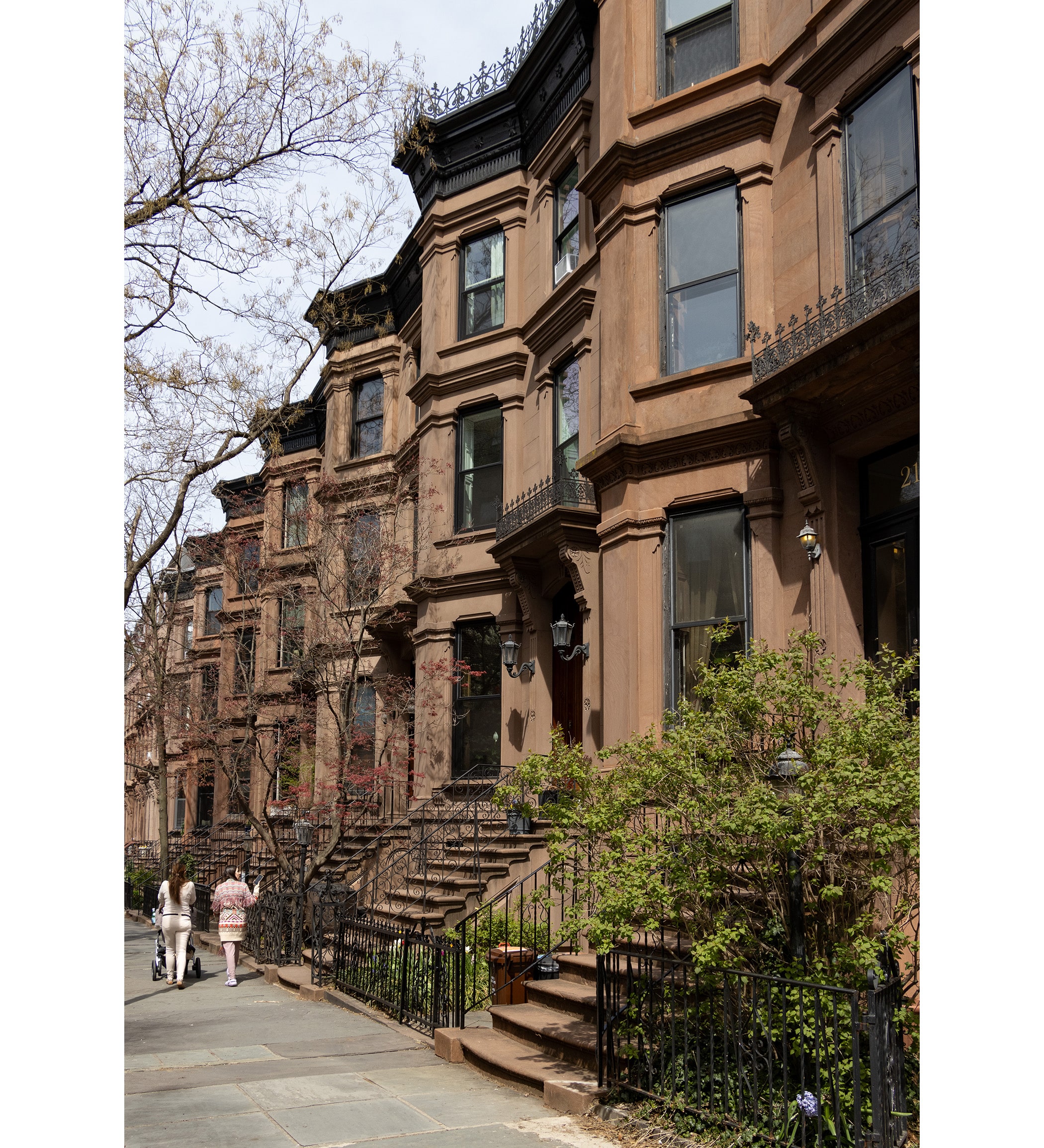 people walking by a brownstone row