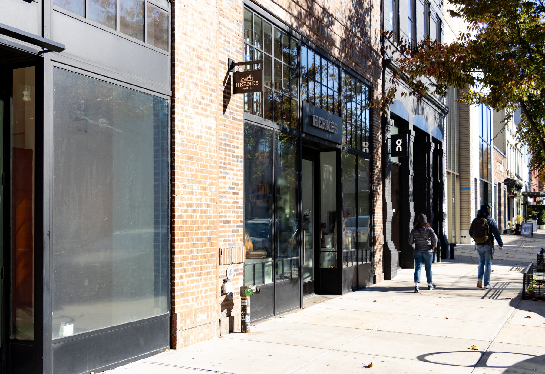 people walking by a hermes storefront