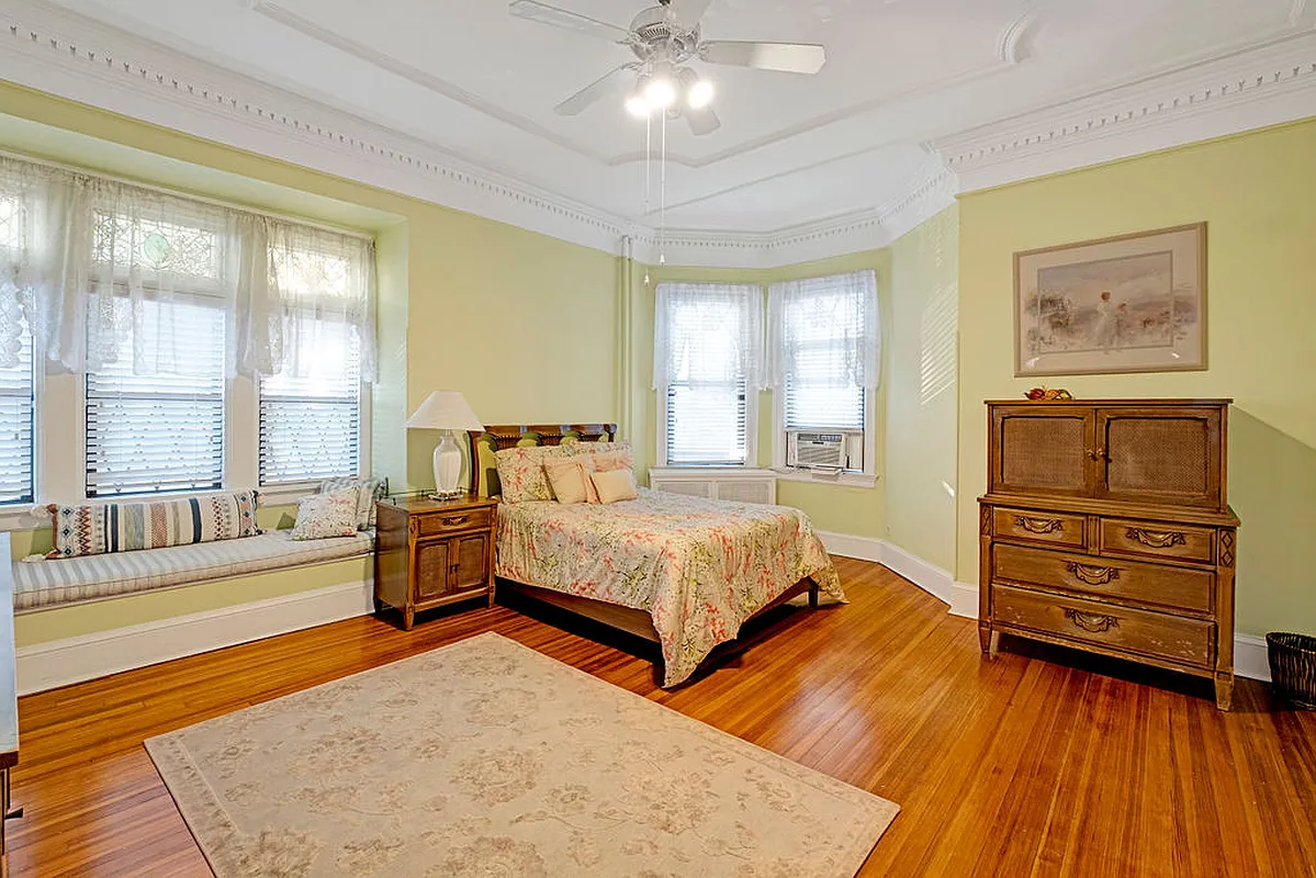 bedroom with window seat, wood floor, plaster details