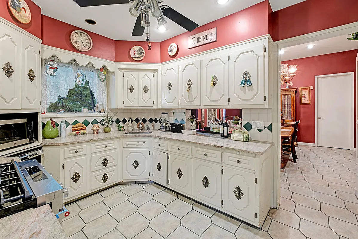 1970s style kitchen with white cabinets and tile