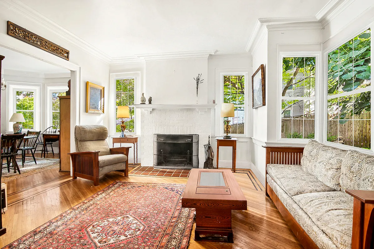 fiske terrace - living room with wood floor, white painted brick fireplace, view into dining room