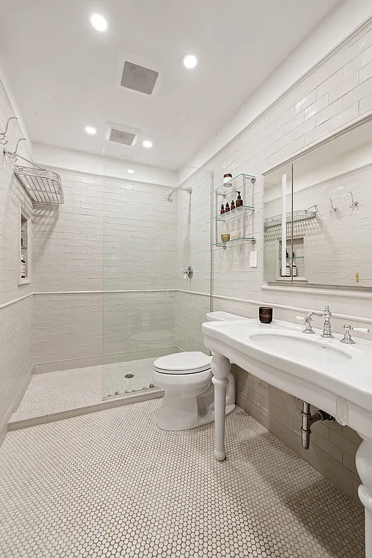 bathroom with a walk-in shower, white console sink and white subway tile on the walls