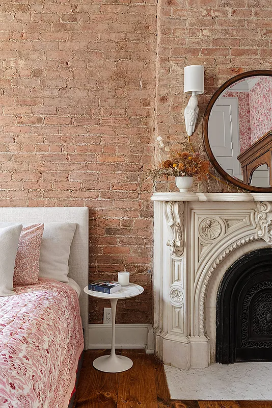 bedroom detail showing exposed brick walls, marble mantel