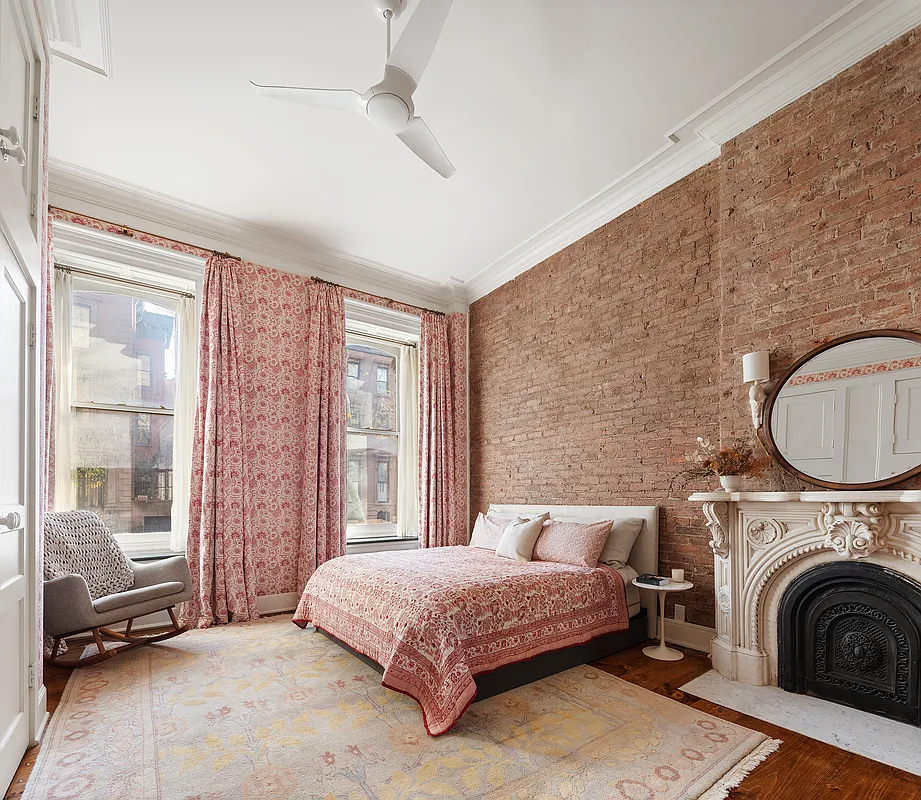 bedroom with an exposed brick wall, a marble mantel and two windows