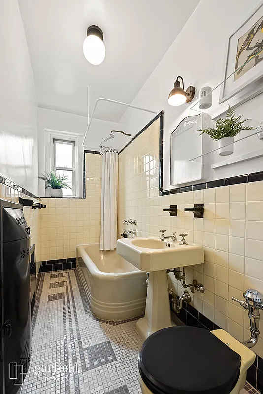 deco bathroom with yellow wall tile and fixtures, black accessories and a patterned tile floor