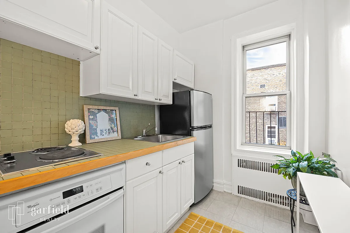 windowed kitchen with green tile countertop and backsplash