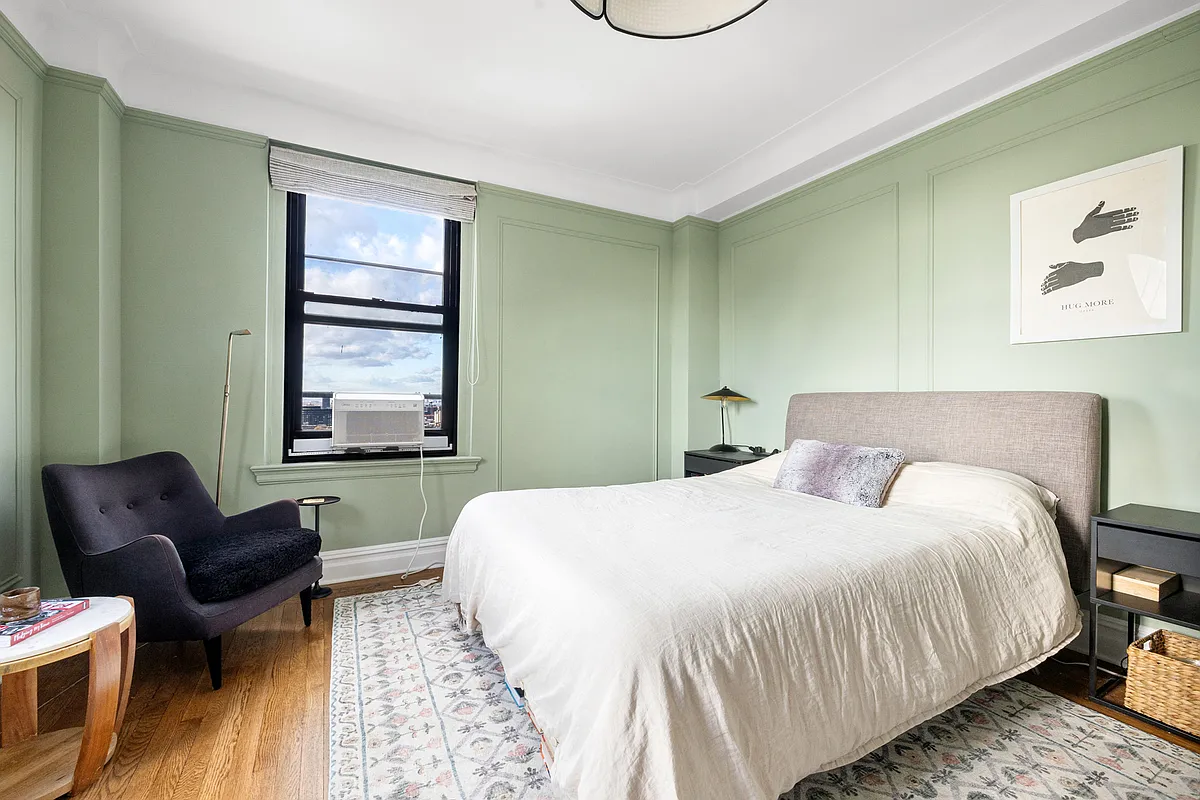 bedroom with pale green walls, wall moldings, and wood floor