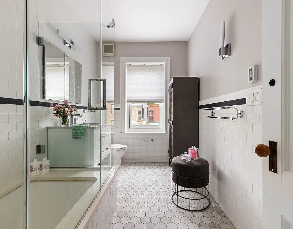 a bathroom with white subway tile and a glass enclosure around the tub