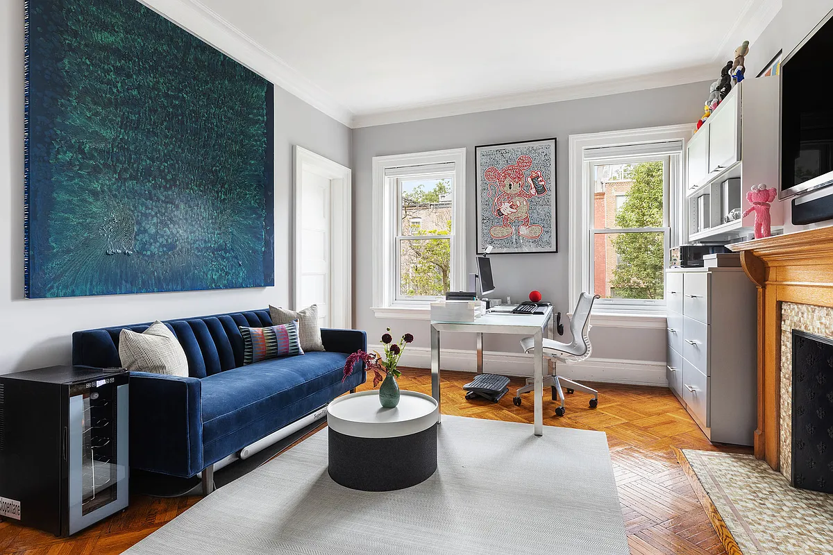 a bedroom with a mantel is set up as a home office