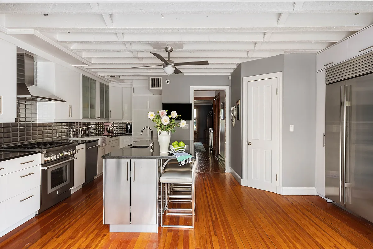 kitchen with white cabinets, exposed rafters, wood floor